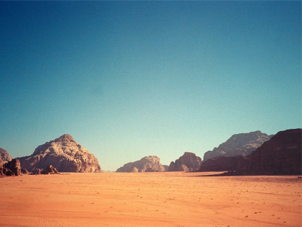 Desert mountain peaks rising above a wide sand plain.